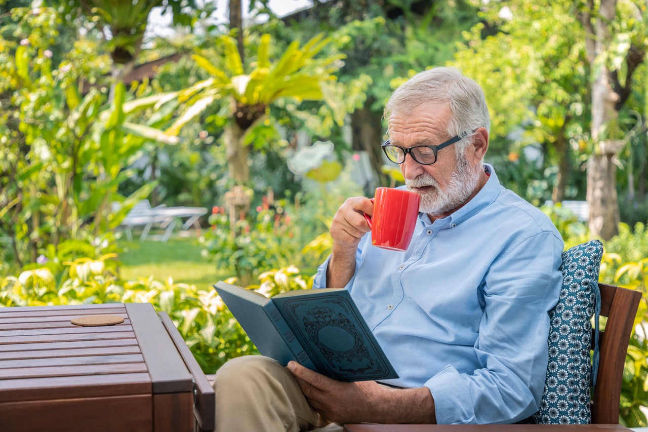 senior elderly man reading book drinking mug coffee garden Large