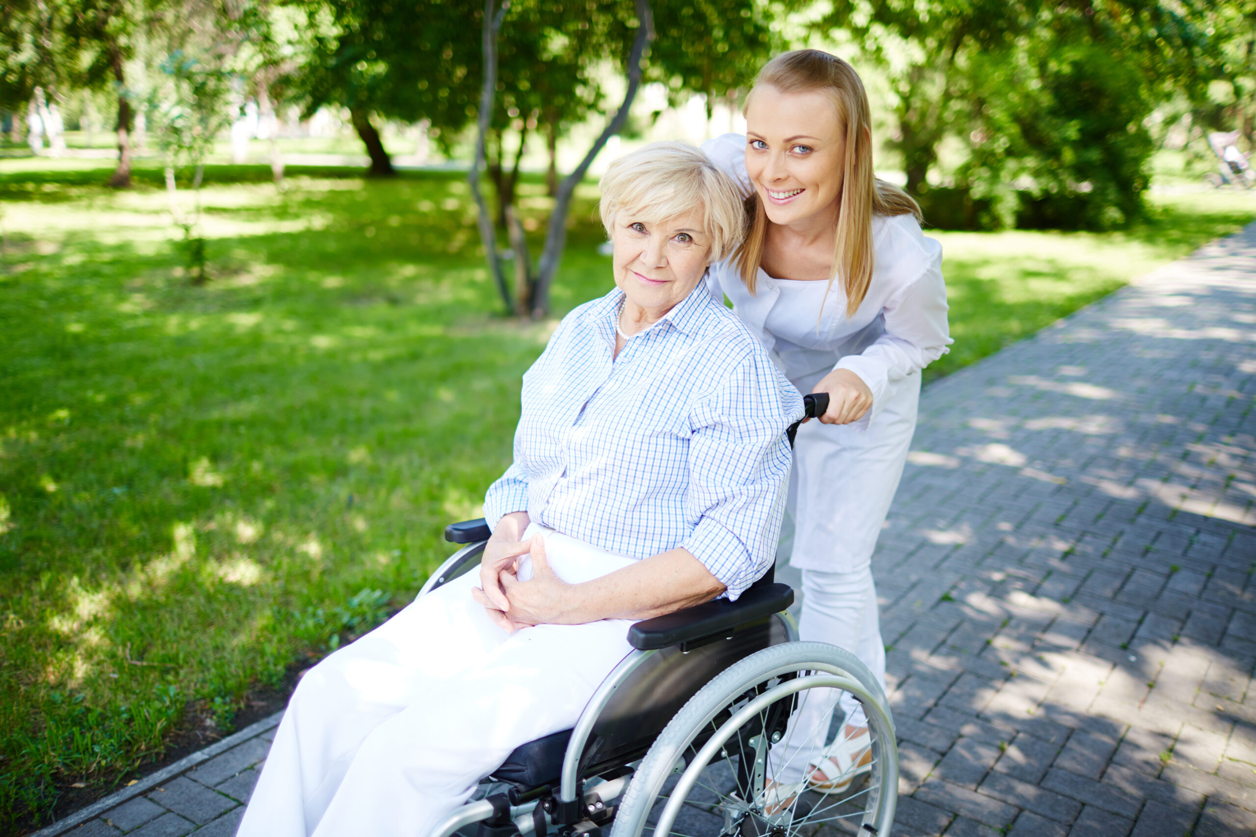 senior woman wheelchair with caregiver outdoors scaled